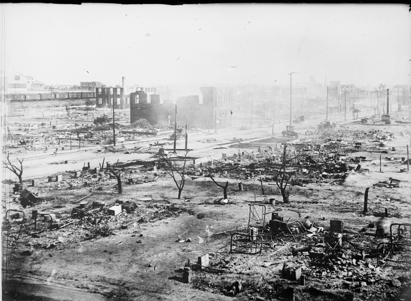 Ruins of Black Wall Street after the Tulsa Race Massacre, showing charred remains and twisted metal amid the devastation.
